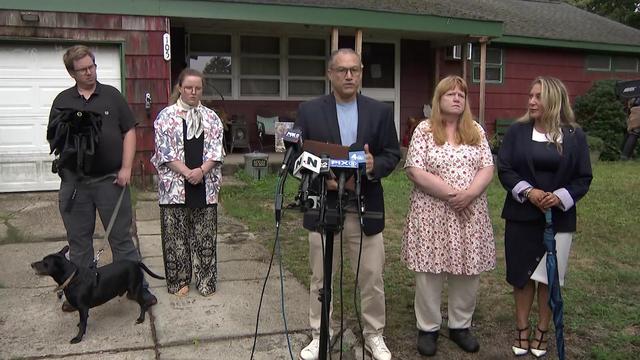 Rex Heuermann's son, daughter and estranged wife stand outside their Massapequa Park home alongside their attorney. 