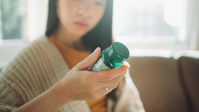 Asian woman choosing between supplements 