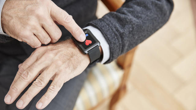 Senior man checking medical data on smartwatch 