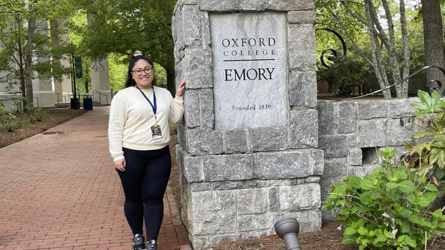 Ashley Rodriguez standing by a sign for Oxford College of Emory University 